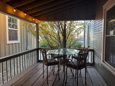 a patio with a glass table and chairs on a porch at Historic King House Above The Keep Tavern