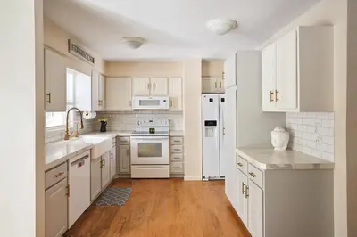 a white kitchen with white appliances and wooden floors at Quiet Guest Space with Hot Tub, Laundry, and Gym in Chagrin Falls