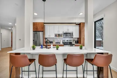a kitchen with a large white island with brown chairs at CWRU & Little Italy Stay with King Bed Gym Parking WD in Cleveland