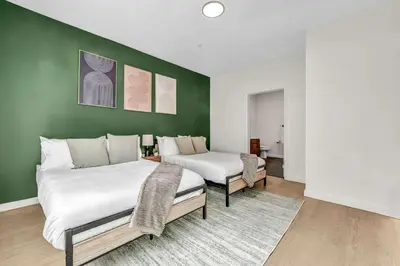 two beds in a room with a green wall at CWRU & Little Italy Stay with King Bed Gym Parking WD in Cleveland