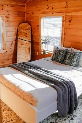 a bedroom with a bed in a wooden cabin at Cedar Wrapped Cozy Villa Cabin - 4 miles from Trails in Laurelville