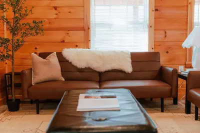 a living room with a brown couch and a table at Cedar Wrapped Cozy Villa Cabin - 4 miles from Trails in Laurelville