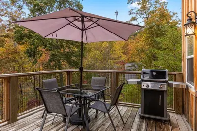 a table and chairs on a deck with an umbrella at The Dragonfly - Tiny Mountaintop Cabin with Hot tub in Stanton