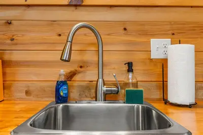 a kitchen sink with a faucet and a roll of paper towels at The Dragonfly - Tiny Mountaintop Cabin with Hot tub in Stanton