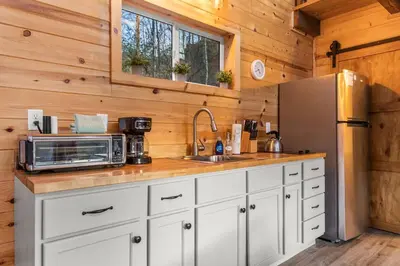 a kitchen with white cabinets and a stainless steel refrigerator at The Hummingbird - Mountaintop Cabin with Hot Tub in Stanton