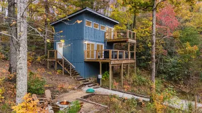 a blue house in the middle of the forest at The Hummingbird - Mountaintop Cabin with Hot Tub in Stanton