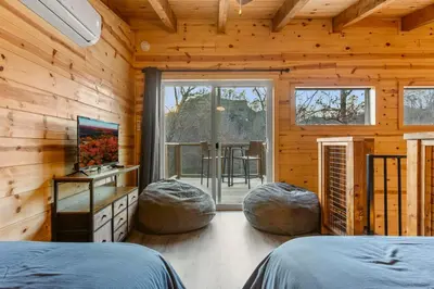 a bedroom with two beds and two stools in a wooden room at The Hummingbird - Mountaintop Cabin with Hot Tub in Stanton