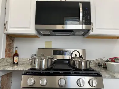 a stove top with two pots and a microwave at Brand new home just minutes from downtown Cincinnati in Cincinnati