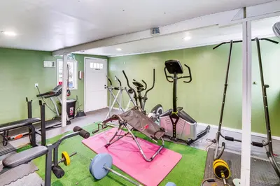 a gym with exercise equipment in a room with green walls at 8 Mi to Dtwn CLE Cozy Couples Retreat with Gym! in Cleveland