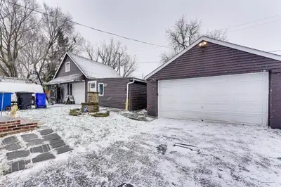 a house with a snow covered yard with a garage at 8 Mi to Dtwn CLE Cozy Couples Retreat with Gym! in Cleveland