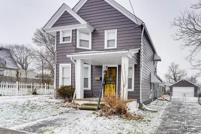 a gray house with a yellow door in the snow at 8 Mi to Dtwn CLE Cozy Couples Retreat with Gym! in Cleveland