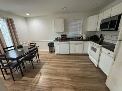 a kitchen with white cabinets and a table and chairs at Spacious 2BR Apartment near Toledo, Sylvania & MI in Toledo