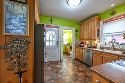 a kitchen with green walls and wooden cabinets and a door at Cozy Berrodin Bed And Breakfast Whole House Booking In Highland Square Akron in Akron