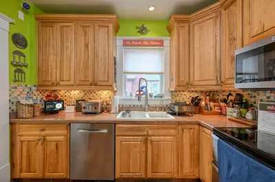 a kitchen with wooden cabinets and a sink and a window at Cozy Berrodin Bed And Breakfast Whole House Booking In Highland Square Akron in Akron