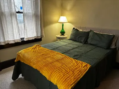 a bedroom with a bed with a yellow blanket on it at The Inn on Holgate Avenue in Defiance