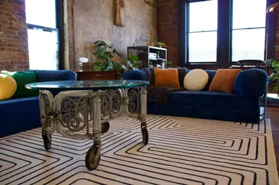 a living room with a blue couch and a glass table at The Historic Berry Loft at Waterfront Hall in Wheeling