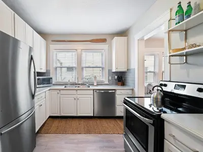 a kitchen with white cabinets and a stainless steel refrigerator at Stylish Lakeside Living - walk to the beach in Cleveland