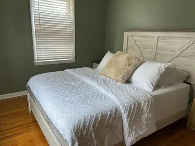 a bed with white sheets and pillows in a bedroom at Charming House, just a short walk to downtown in Vermilion