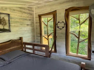 a bedroom with a bed and two windows at The Royal Roost Treehouse