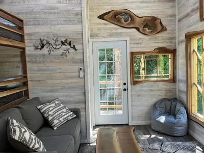 a living room with a couch and a door at The Royal Roost Treehouse