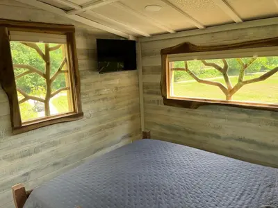 a bedroom with a bed and two windows at The Royal Roost Treehouse