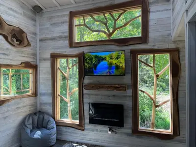 a room with four windows and a tv and a couch at The Royal Roost Treehouse