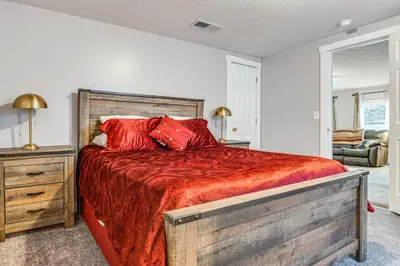 a bedroom with a large bed with a red comforter at Pets Welcome! Quiet Economy Home with Spacious Yard in Economy