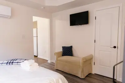 a bedroom with a bed and a chair and a television at Big Blue - Stylish Studio in Downtown Lexington in Lexington