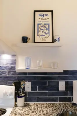 a kitchen with blue tiled walls and a shelf at Big Blue - Stylish Studio in Downtown Lexington in Lexington