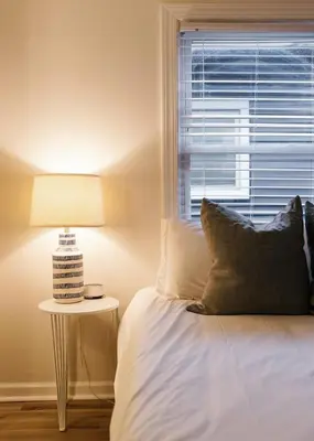 a bed with a lamp next to a window at Big Blue - Stylish Studio in Downtown Lexington in Lexington