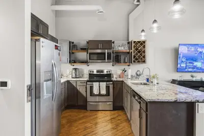 a kitchen with stainless steel appliances and wooden floors at Speakeasy Attached, Walkable to Cavs, Flats, Casino in Cleveland