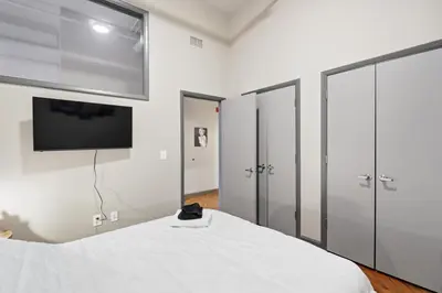 a bedroom with a white bed and a flat screen tv at Speakeasy Attached, Walkable to Cavs, Flats, Casino in Cleveland