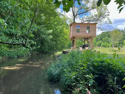 a tree house sitting on the side of a river at The Owl's Perch Treehouse