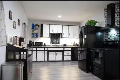 a kitchen with white cabinets and a black refrigerator at Hot Tub Arcadia