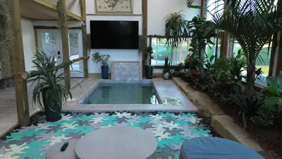 a swimming pool with a tv in a room with plants at The Conservatory at Owl Hollow in Woodsfield