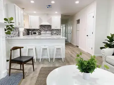 a kitchen and living room with white cabinets and a table at Gardenia - Stylish Apartment in Downtown Lexington in Lexington