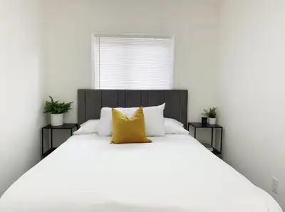 a large white bed with a yellow pillow on it at Gardenia - Stylish Apartment in Downtown Lexington in Lexington