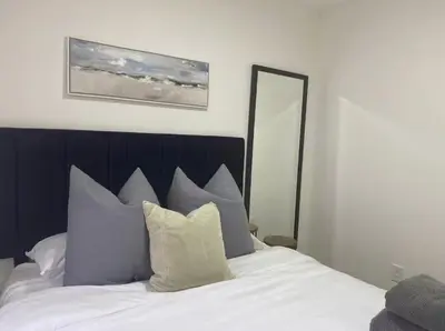 a bedroom with a bed with white sheets and a mirror at Gardenia - Stylish Apartment in Downtown Lexington in Lexington
