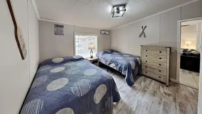 a bedroom with two beds and a dresser and a mirror at Put-in-Bay Island Club #106 in Put-in-Bay