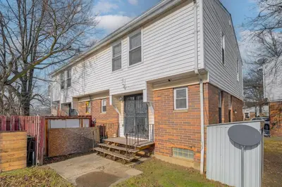 a white house with a gate and a brick building at Red Line to Downtown! Inviting Home in Cleveland in Cleveland