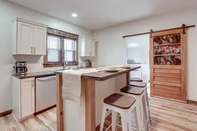 a kitchen with white cabinets and a counter with stools at Amish Country Escape Decatur Family Farmhouse in Decatur