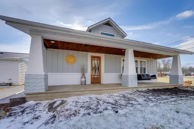 a white house with a porch in the snow at Amish Country Escape Decatur Family Farmhouse in Decatur