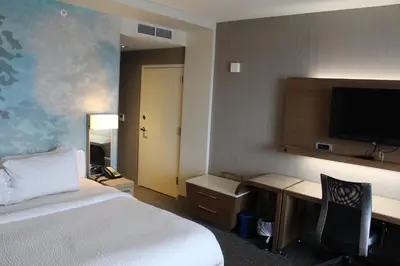 a hotel room with a bed and a desk and a television at Courtyard by Marriott Muncie at Horizon Convention Center in Muncie