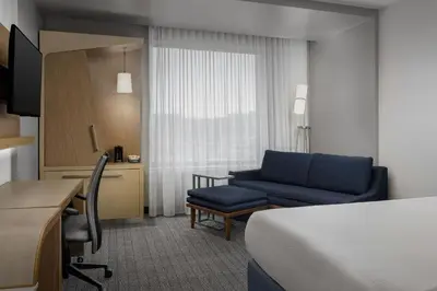 a hotel room with a bed and a blue couch at Courtyard by Marriott Muncie at Horizon Convention Center in Muncie
