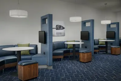 a waiting room with couches and tables and televisions at Courtyard by Marriott Muncie at Horizon Convention Center in Muncie