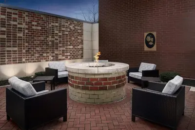 a patio with a fountain and chairs and a brick wall at Courtyard by Marriott Muncie at Horizon Convention Center in Muncie
