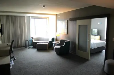 a hotel room with a bed and chairs and a bedroom at Courtyard by Marriott Muncie at Horizon Convention Center in Muncie