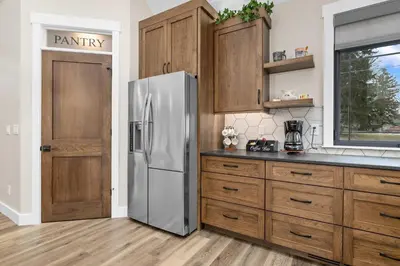 a kitchen with a stainless steel refrigerator and wooden cabinets at Luxury Modern Lodge Near Fort Wayne with River Views