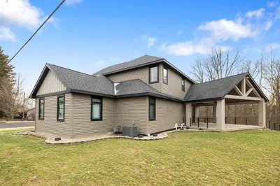 a house with a black roof on a yard at Luxury Modern Lodge Near Fort Wayne with River Views