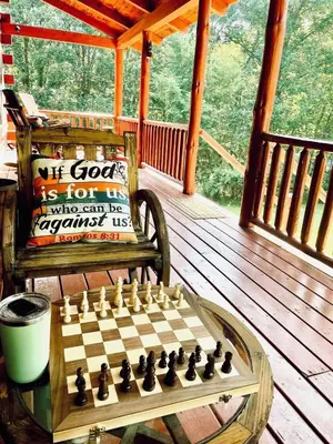 a chess board on a table on a porch at Breath of Heaven Cabin- Hot Tub, Deck, Pond, PETS in Logan